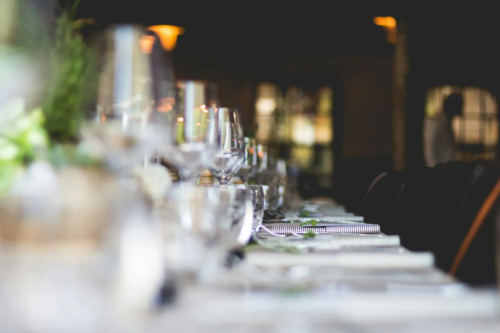 Elegant candlelit reception table set with crystal glassware and greenery in soft focus