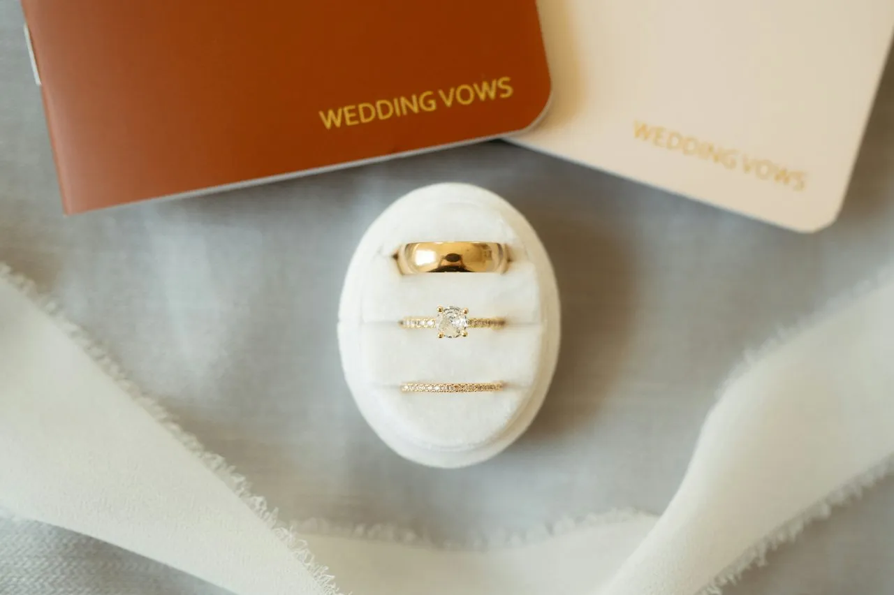 Two wedding vow booklets in cream and terracotta with gold rings in a velvet ring box