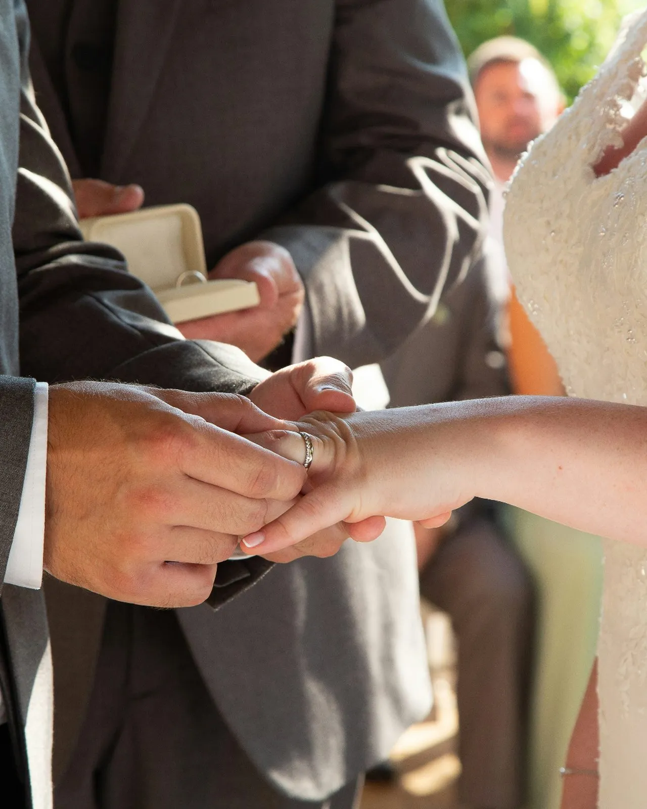 Couple holding hands during the ring exchange at an intimate outdoor wedding ceremony