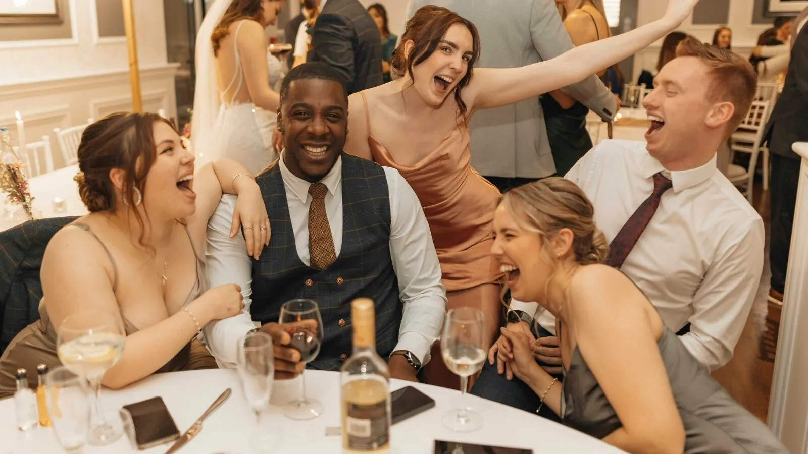 Wedding guests laughing and celebrating together at a reception table